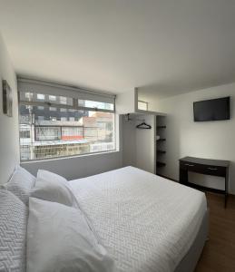 a bedroom with a white bed and a window at HOSTELFC CORFERIAS in Bogotá
