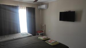 Un dormitorio con una cama y un televisor en la pared. en Belmar Santa Teresita, en Santa Teresita