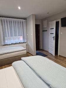 two beds in a room with a window and a door at Noclegi u Alicji- Apartamenty in Gołuchów