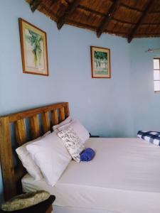 1 dormitorio con 1 cama con sábanas y almohadas blancas en Slubani, en Eshowe