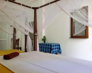 a bedroom with a white bed with a canopy at Happy house mirissa in Kamburugamuwa