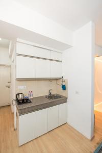 a kitchen with white cabinets and a sink at Skystay Apartments in Lucknow