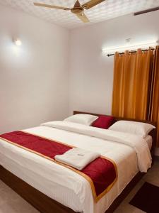 a bedroom with a large bed with red and white sheets at PONMUDI VILLA in Ambalavayal