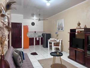 a living room with a couch and a tv and a kitchen at Casa Tatich AC near Guanacaste Airport in Liberia