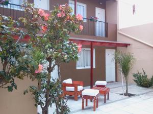 Un edificio con sillas y un árbol delante. en Belmar Santa Teresita, en Santa Teresita