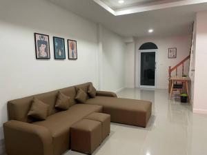 a living room with a brown couch and a table at Home One บ้านพักรายวัน in Buriram