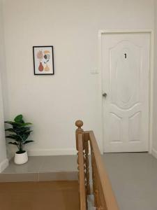 a hallway with a white door and a potted plant at Home One บ้านพักรายวัน in Buriram