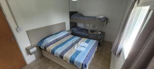 Un dormitorio pequeño con una cama con una manta de rayas. en Rio Grande, en Neuquén