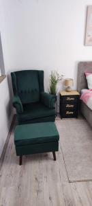 een groene stoel en een poef in een slaapkamer bij STUDIO APARTMAN PAVIĆ in Vinkovci