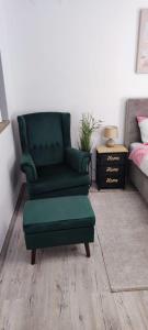 a green chair and a ottoman in a bedroom at STUDIO APARTMAN PAVIĆ in Vinkovci