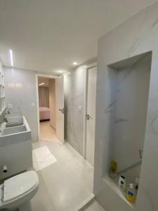 a white bathroom with a toilet and a sink at Bangalô na praia in Cabedelo