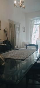 uma mesa de vidro numa sala de estar com uma guitarra em A s'antiga em Seùlo