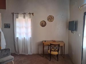 Zimmer mit einem Tisch, einem Stuhl und einem Fenster in der Unterkunft La Fandenoise in Thiès