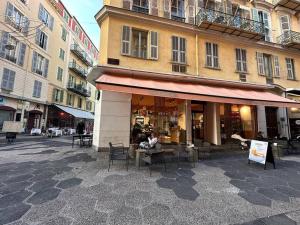 een gebouw met tafels en stoelen in een stadsstraat bij Joli 2 pièces bien placé avec clim à 300m de la plage in Nice