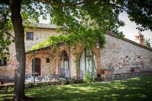 une vieille maison en briques avec un arbre dans la cour dans l'établissement Agriturismo Monacianello - Fontebelvedere wine estate, à Ponte A Bozzone