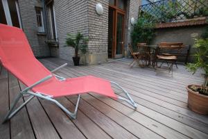 una silla roja sentada en una terraza de madera en REIMS-ESCAPADE terrasses, en Reims