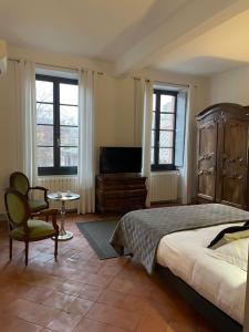 a bedroom with a bed and a tv and a chair at B&B Les chambres d'Aim&eacute; in Carcassonne