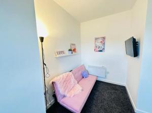 a pink couch in a room with a tv at Comfy Stylish 1BD Apt near Transport Links in Liverpool