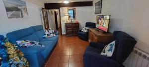 sala de estar con sofá azul y 2 sillas en La Casa de Su en Baños de Montemayor