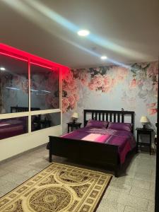 1 dormitorio con 1 cama con sábanas y flores púrpuras en ابراج المسارات en Yeda