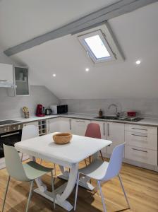 - une cuisine avec une table et des chaises blanches dans l'établissement Appartement Les nuits de 3 Centre-ville, à Troyes