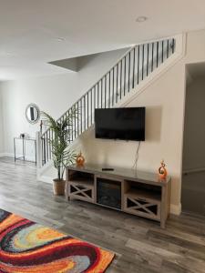 a living room with a television and a staircase at New Walkerville Cozy Brownstones in Windsor