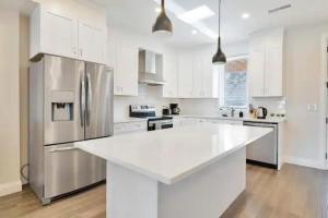 a kitchen with white cabinets and a stainless steel refrigerator at New Walkerville Cozy Brownstones in Windsor