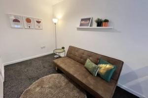 a living room with a brown couch with two pillows at Minimalist 1Bed Apt near City Centre in Liverpool