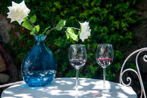 tres copas de vino sentadas en una mesa con un jarrón azul en La Casa de Su en Baños de Montemayor