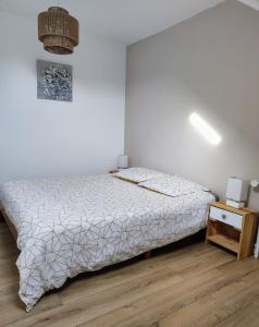 - une chambre blanche avec un lit et une table de nuit dans l'établissement Appartement Les nuits de 3 Centre-ville, à Troyes