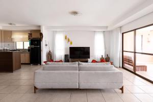 uma sala de estar com dois sofás brancos e uma cozinha em Oceanview A102 - PÉ NA ÁREA - perto do centro, 2 dormitórios, piscina, cozinha, 116m2 em Cumbuco