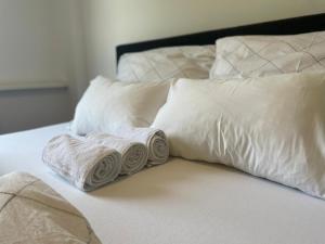 zwei gerollte Handtücher auf einem Bett mit Kissen in der Unterkunft Linz Central Apartment in Linz