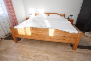 - une chambre avec un lit en bois et des draps blancs dans l'établissement Casa De Vacanta Armi, à Molidu
