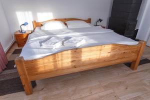 a wooden bed with white sheets and towels on it at Casa De Vacanta Armi in Molidu