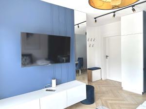 a living room with a tv on a blue wall at DMK Blue Apartment near Warsaw-Modlin Airport in Nowy Dwór Mazowiecki