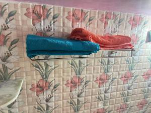 a shelf with towels on a wall with flowers at Peaceful Spacious Private 1BHK Near Airport close to VIP or Jessore Rd in Nager Bazaar