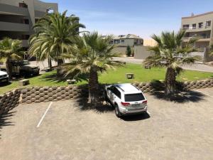 un coche aparcado en un aparcamiento con palmeras en ST Chris Villa en Langstrand