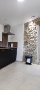 uma cozinha com uma parede de pedra e um balcão em Le gîte de la vieille pierre 'climatisé' em Allex