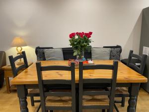 a dining room table with a vase of roses on it at Bungalow33 Benllech in Benllech