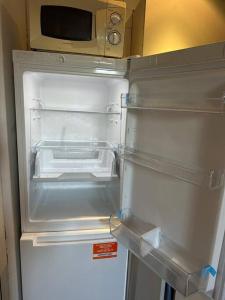 an empty refrigerator with its door open in a kitchen at Entire Modern Studio Apartment with Pool Table in Denton