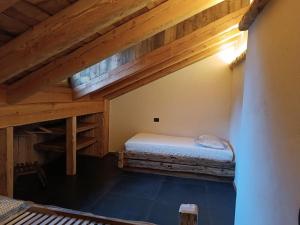 een zolderkamer met een bed en houten plafonds bij Brand new duplex in the Dolomites - Lupo Bianco in Rocca Pietore