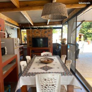 a dining room with a table and chairs and a television at La Villa d'Elyas in Sainte-Suzanne