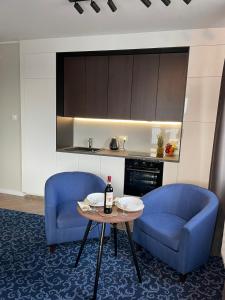 a kitchen with two blue chairs and a table with a bottle of wine at Premium Apartment Victoria 141 in Warsaw
