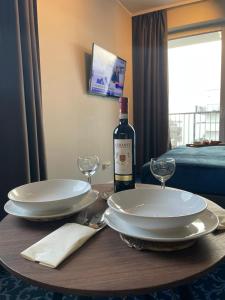 a table with two white plates and a bottle of wine at Premium Apartment Victoria 141 in Warsaw