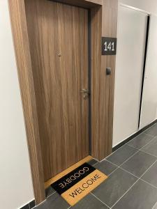 a wooden door with a welcome mat in front of it at Premium Apartment Victoria 141 in Warsaw
