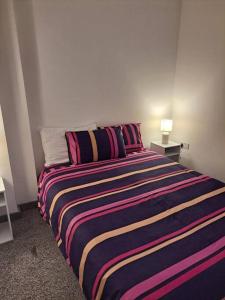 a bedroom with a large bed with a colorful striped blanket at 1 Bedroom Flat Available in Oldham