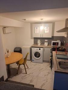 a kitchen with a table and a stove and a washing machine at 1 Bedroom Flat Available in Oldham +7 photos