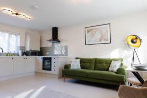a living room with a green couch and a kitchen at Stylish 1 bed apartment with free parking in Cardiff