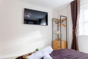 a bedroom with a bed with a tv on the wall at Stylish 1 bed apartment with free parking in Cardiff