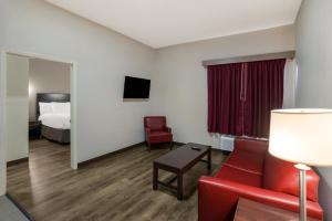 a hotel room with a red couch and a bed at Rodeway Inn in Brandon